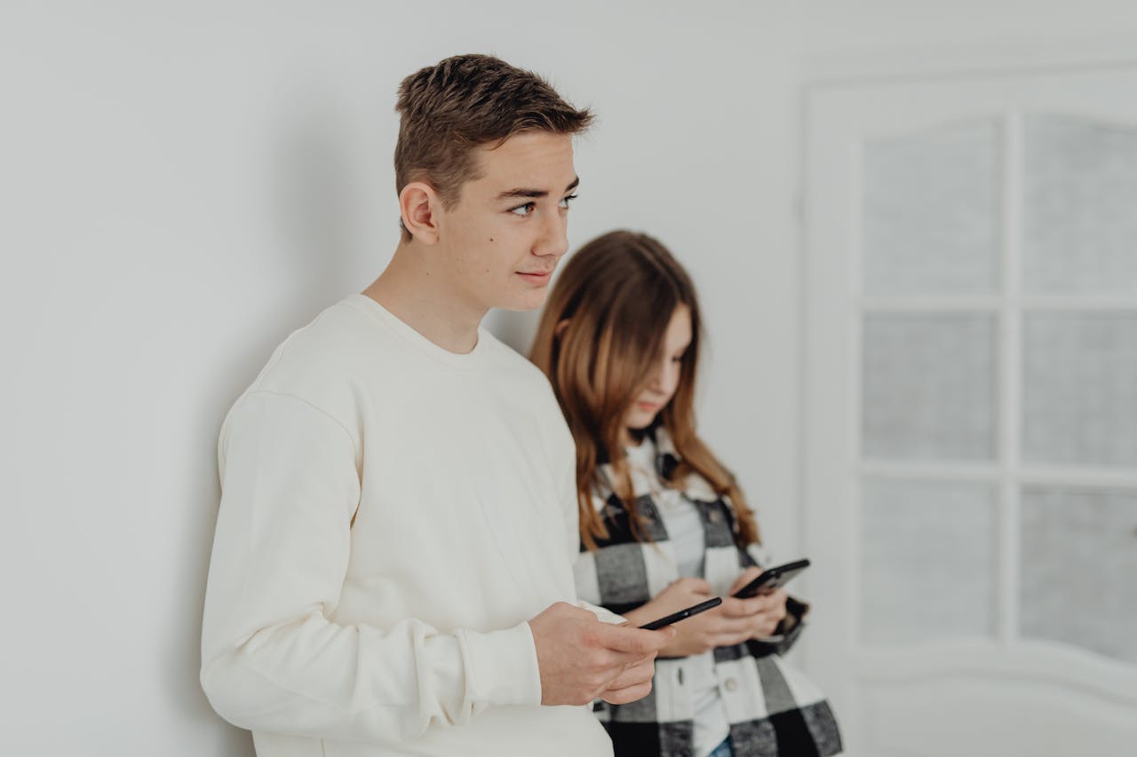 Two teenagers using smartphones, focusing on communication indoors.